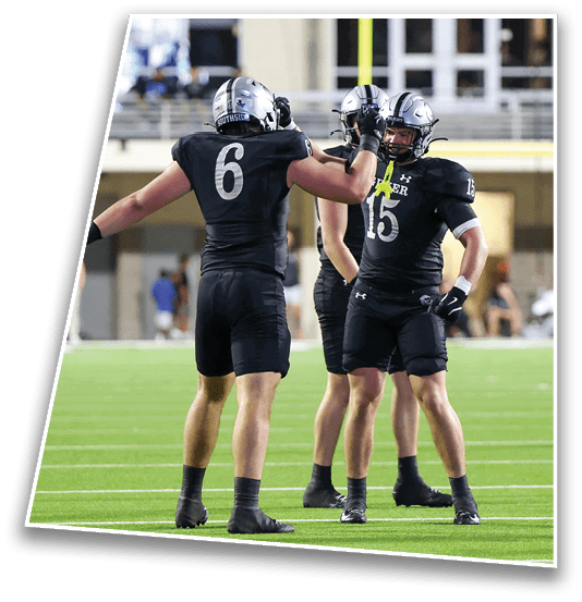 Three people in black football uniforms are on a field with one person in a white and red uniform sitting on the ground nearby. Description generated by AI