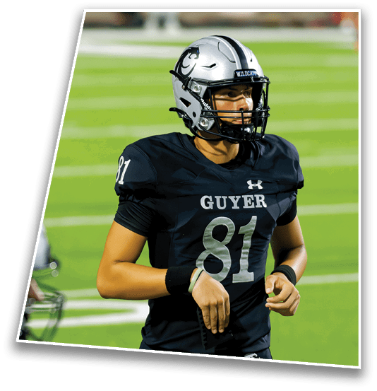 A person wearing a football uniform with the number 81 and a helmet stands on a green field during a game. Description generated by AI