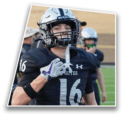 A person in a football uniform with the number 16 is holding a sword-shaped mouthguard while standing on a football field with other players in the background. Description generated by AI