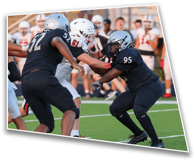 People wearing football uniforms and helmets are engaged in a play on a green field with one player in black pushing against a player in white. Description generated by AI