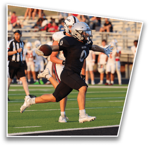 A person wearing a black football uniform with the number zero is running on a field with arms outstretched while other players in white uniforms stand in the background. Description generated by AI