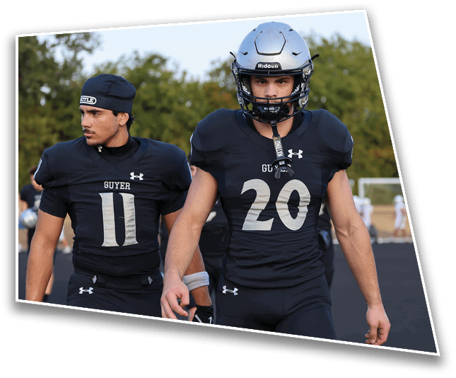 Two people wearing black football uniforms with the numbers 11 and 20 are standing outdoors on a sports field. Description generated by AI