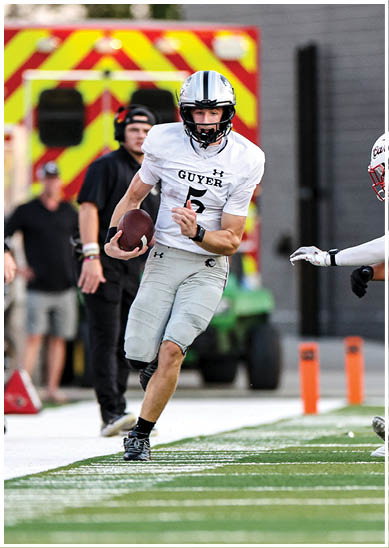 A person wearing gray athletic shorts and black shoes is running on a football field while holding a football. Description generated by AI