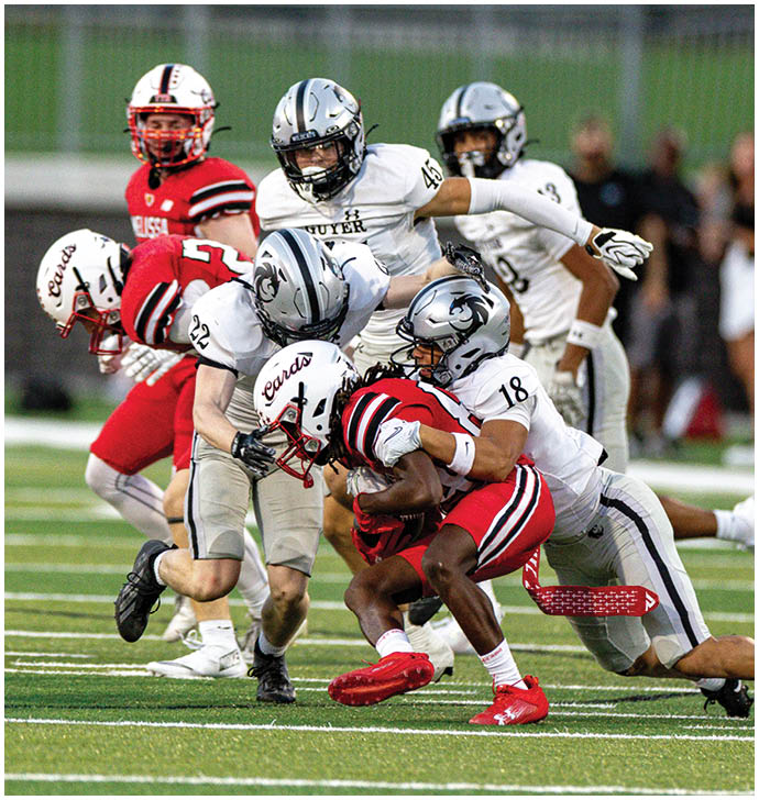 People wearing football helmets and uniforms are engaged in a game on a field. Description generated by AI