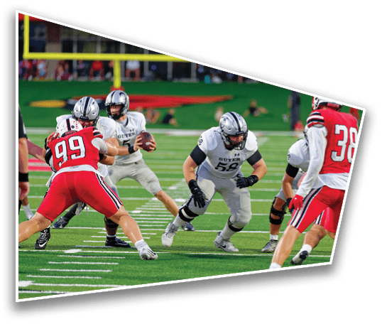 Adults in football uniforms are actively playing a game on a green field with white yard lines, with one player holding the ball and others preparing to block or tackle. Description generated by AI