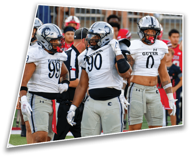 People in football uniforms are on a field with a referee signaling a call while spectators watch from the stands. Description generated by AI