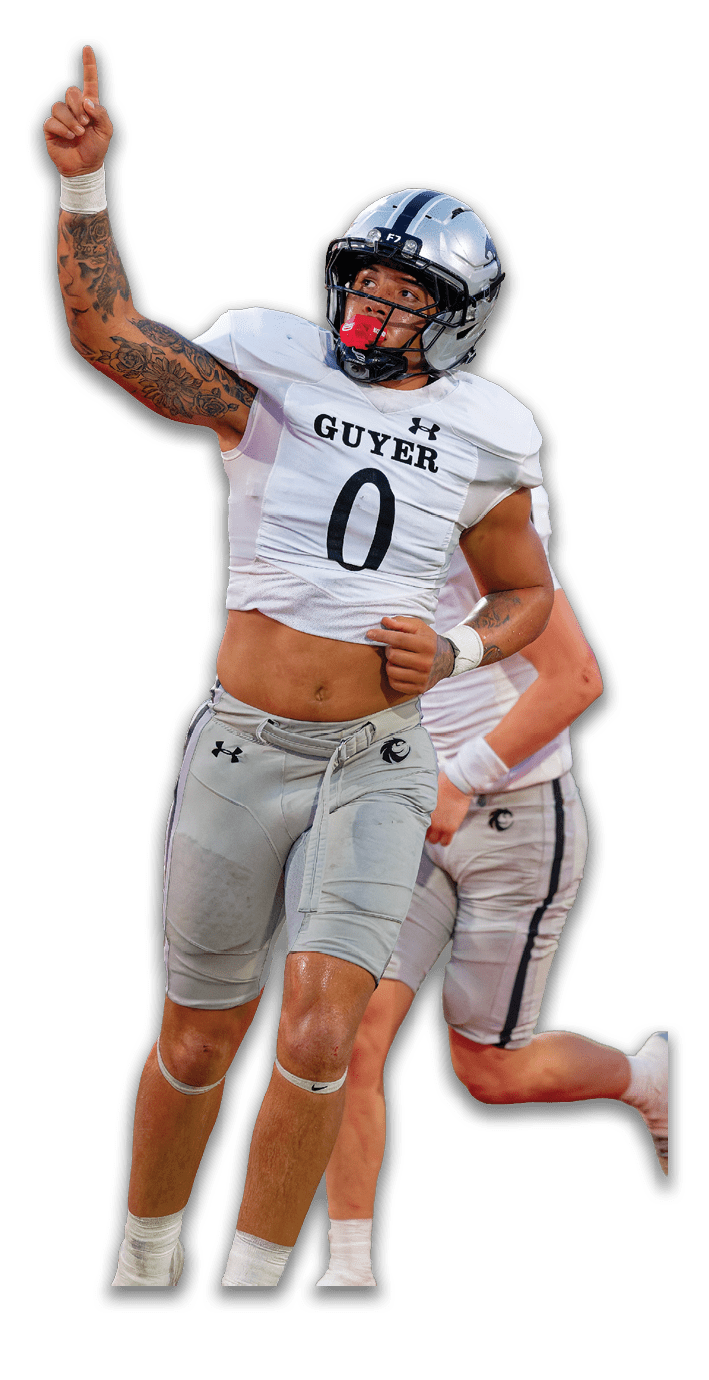 A person wearing a football uniform with a helmet and a tattooed arm is raising one arm while preparing to throw a football. Description generated by AI