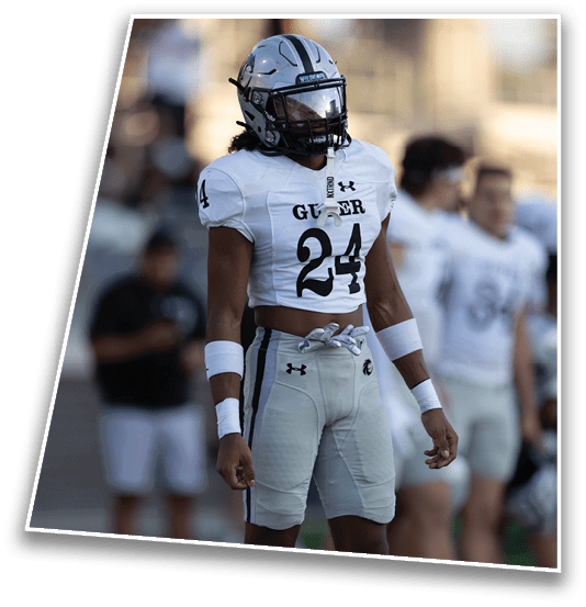 A person wearing a white football uniform with the number 24 and a silver helmet stands on a field with a blurred background. Description generated by AI