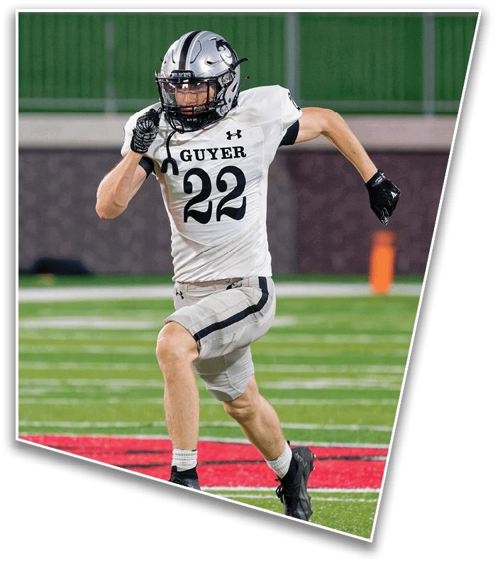 A person wearing a silver football helmet and a white jersey with the word “GUYER" is running on a field. Description generated by AI