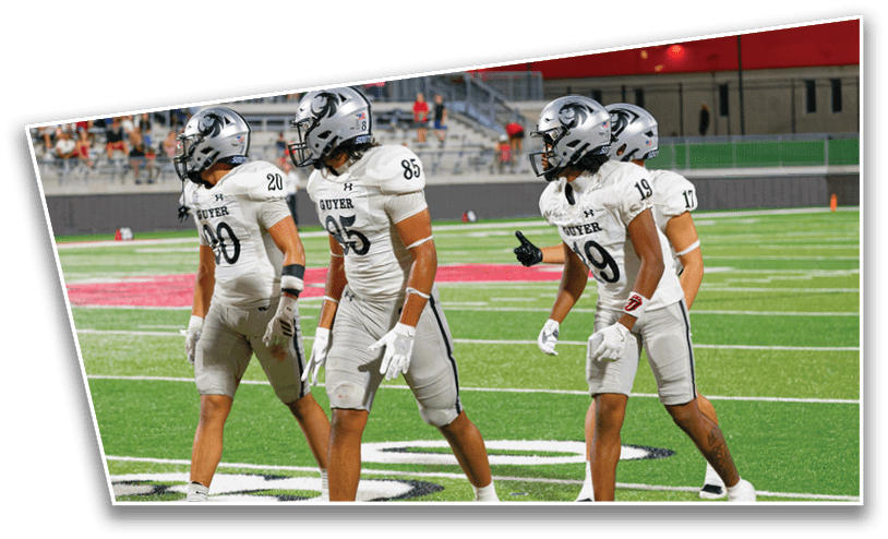 Four people in white football uniforms and helmets walk together on a green football field. Description generated by AI