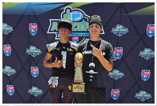 Two people stand side by side holding a football trophy in front of a backdrop featuring Arizona Football League logos. Description generated by AI