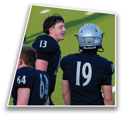 Three people wearing dark football uniforms with numbers 13 and 10 are on a green field, with one person wearing a silver helmet. Description generated by AI