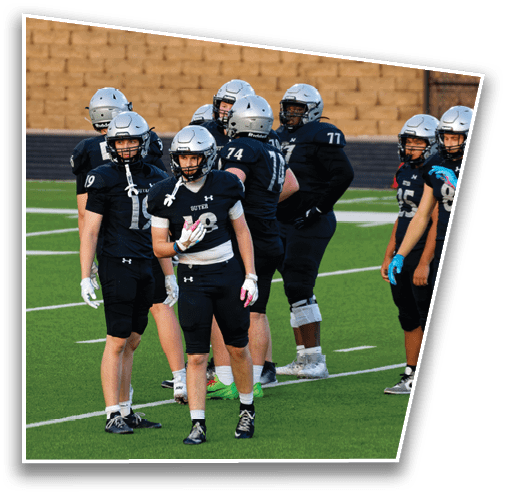 Several people wearing athletic clothing and cleats are standing on a green sports field with white lines. Description generated by AI
