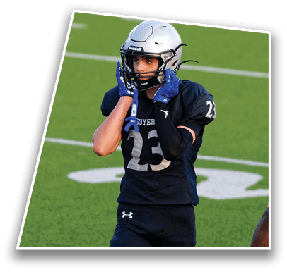 A person wearing a silver football helmet and blue gloves is adjusting the helmet while standing on a green field. Description generated by AI