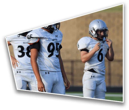 Three people wearing white football uniforms and helmets stand on a field with a blurred background. Description generated by AI