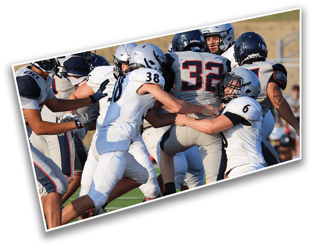 People wearing football uniforms are engaged in a play on a grassy field with some players tackling and others running. Description generated by AI