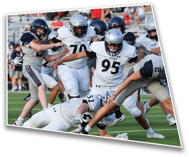Several people wearing football uniforms are actively engaged in a play on a football field, with some players tackling or blocking others. Description generated by AI