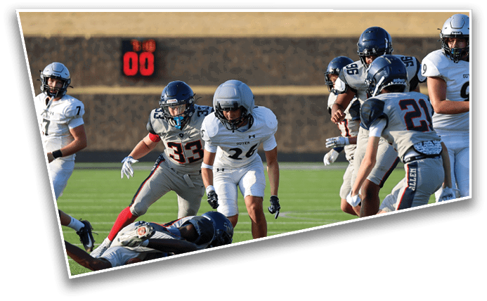 People in football uniforms are actively playing on a field with one person on the ground and others running or preparing to engage. Description generated by AI