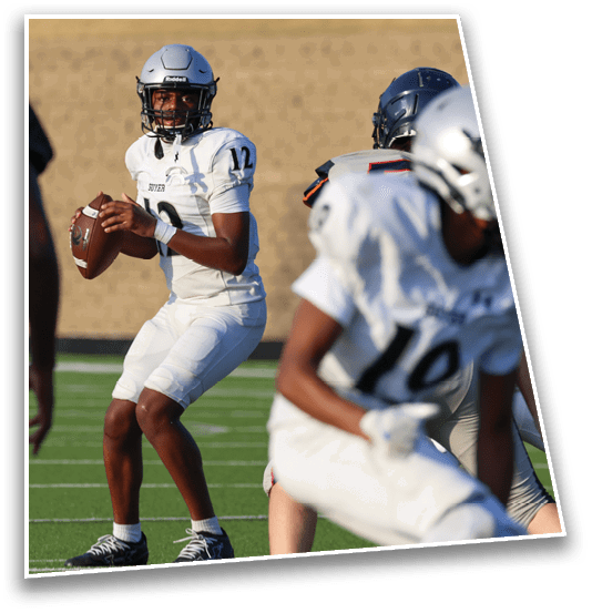 Several people wearing football helmets and uniforms are engaged in a game on a green field with a blurred background. Description generated by AI