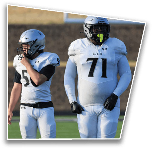 Two people wearing white football uniforms and helmets stand side by side on a field, one adjusting their helmet and the other with a mouthguard. Description generated by AI