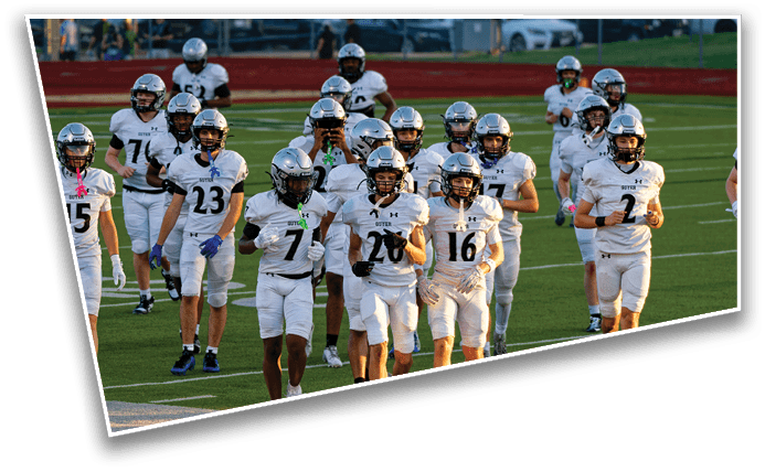 A group of people wearing white football uniforms and helmets are walking together on a green football field. Description generated by AI