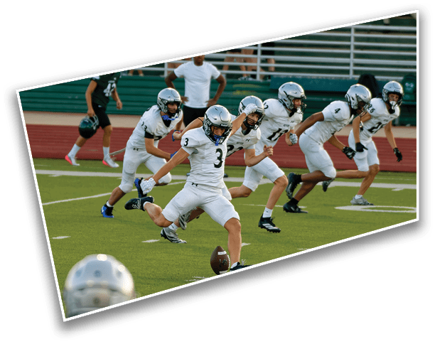 A group of people in white football uniforms and helmets are running on a field as one person kicks a football. Description generated by AI