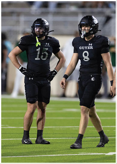 A person wearing a black football helmet and black uniform with the word Wildcats on the helmet is on a field with blurred spectators in the background. Description generated by AI