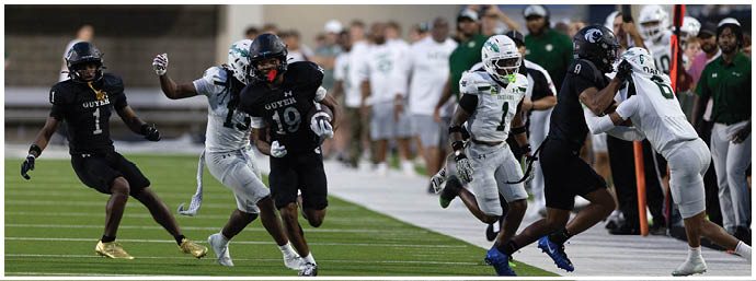 People in football uniforms are actively running and competing on a field during a game. Description generated by AI