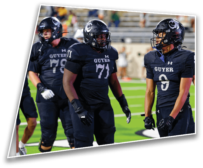 Three people wearing black football uniforms with helmets are standing on a green field during a game. Description generated by AI
