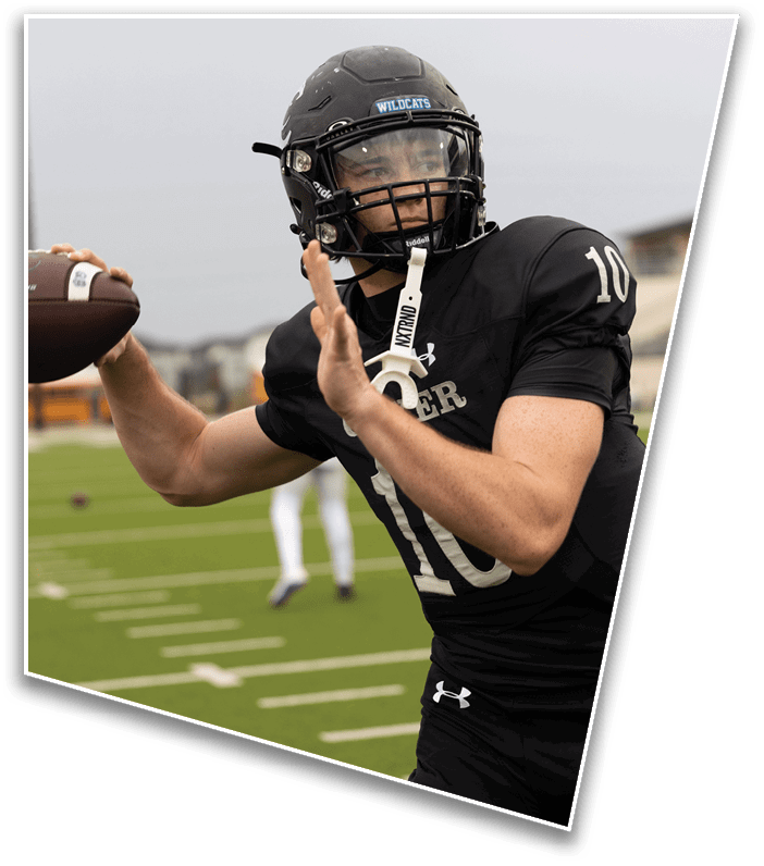 A person wearing a black football uniform and helmet is preparing to throw a football on a field. Description generated by AI
