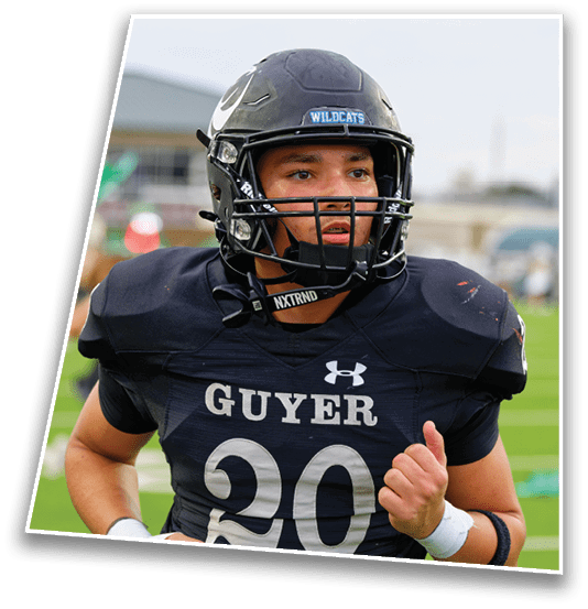 A person wearing a black football uniform and helmet with the word Wildcats on the helmet and Guyer on the jersey is on a football field. Description generated by AI