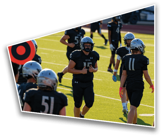 Several people wearing black football uniforms and helmets are standing and walking on a sunlit green field. Description generated by AI