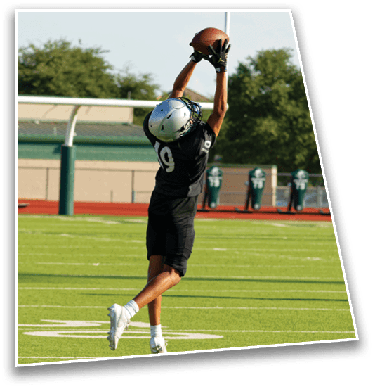 Two people in football uniforms and helmets are celebrating on a football field with one person jumping and the other running. Description generated by AI