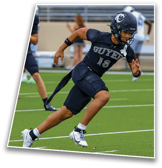 A person wearing a black football uniform with the number 16 is running on a green field during a game. Description generated by AI