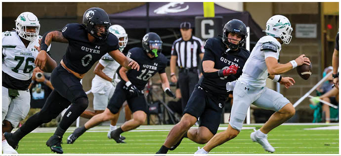 Adults in football uniforms are actively playing a game on a field with one person in white running with the ball while others in black attempt to catch them. Description generated by AI