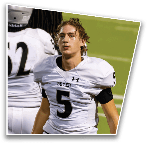 A person wearing a white football uniform with the number 5 and the word “GUYER" on the chest stands on a green field. Description generated by AI
