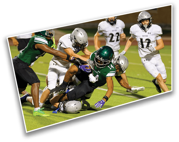 Several people in football uniforms are engaged in a tackle on a grassy field during a game. Description generated by AI