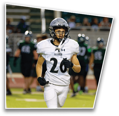 Two people in football uniforms are engaged in a play on a field, with one person holding the ball and the other reaching out to tackle. Description generated by AI