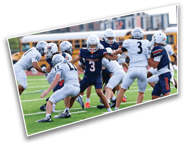 Players in football uniforms are actively engaged in a play on a green field with white yard lines. Description generated by AI