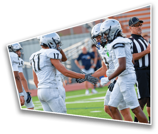 People in football uniforms are on a field shaking hands while a referee stands nearby. Description generated by AI