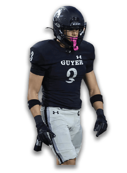 A person wearing a black football uniform with the number three and a helmet is walking with a pink mouthguard in their mouth. Description generated by AI
