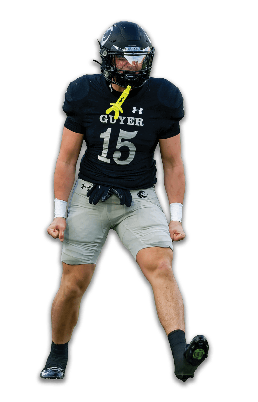 A person wearing a black football uniform with the number 15 and the word Guyer on the chest is holding a yellow mouthguard in their mouth while wearing a black helmet with a reflective visor and the word Wildcats on the front. Description generated by AI