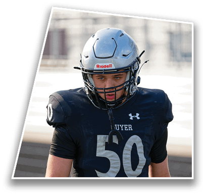 A person wearing a black football uniform with the number 50 and a silver helmet is standing outdoors on a sports field. Description generated by AI