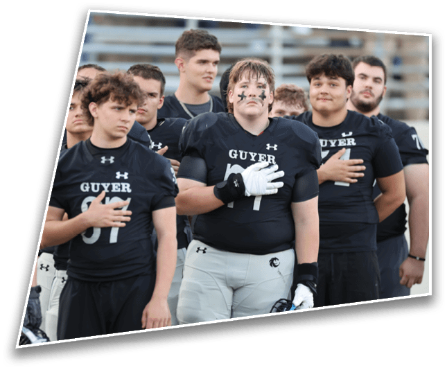 A group of people wearing black football jerseys with “GUYER" written on them stand with their hands over their hearts, appearing focused and solemn. Description generated by AI