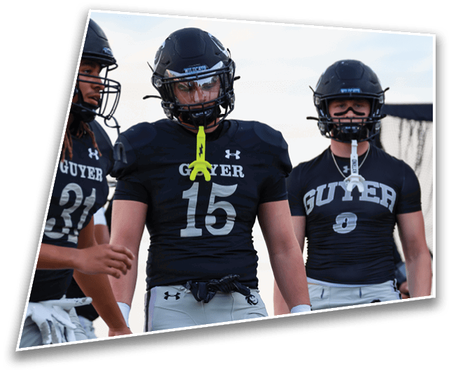 Three people wearing black football helmets and black jerseys with the word “GUTYER" stand outdoors against a blue sky. Description generated by AI