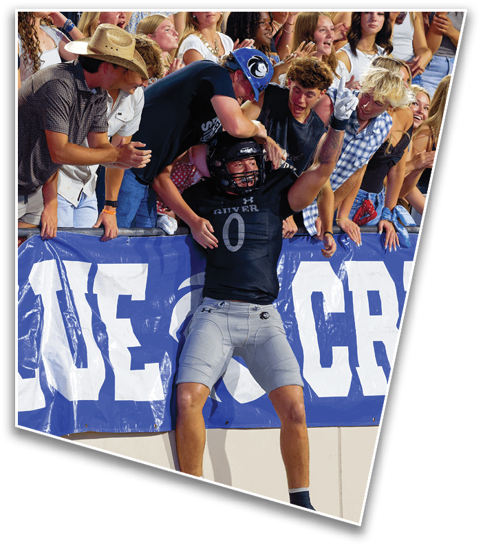 A crowd of enthusiastic people wearing casual clothing and hats are cheering and interacting closely at an outdoor event. Description generated by AI