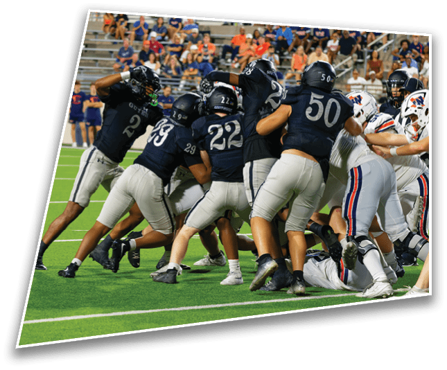 A group of people wearing dark and white football uniforms are engaged in a play on a green football field with spectators in the background. Description generated by AI