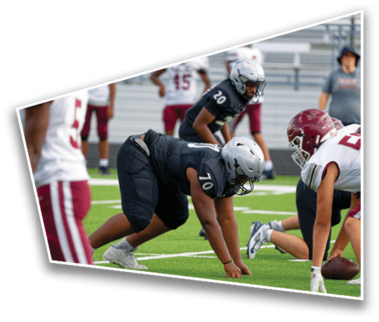 Two teams of people in football uniforms are lined up facing each other on a field, preparing for a play. Description generated by AI