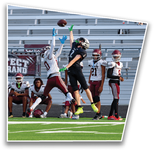 Several people in sports uniforms are sitting and standing on the sidelines of a football field with a banner that reads “Protect the Brand" behind them. Description generated by AI