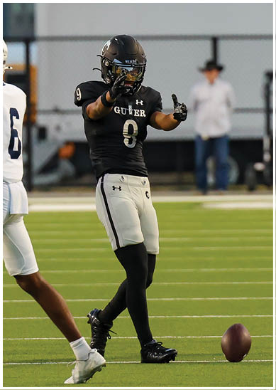 Two people in football uniforms are on a field, with one wearing a black jersey and the other wearing a white jersey. Description generated by AI